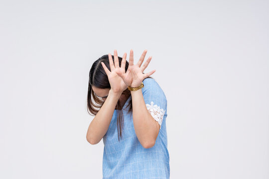 Fearful Asian woman protecting herself with hands isolated on white
