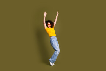 Fototapeta na wymiar Full length photo of funky woman wear sunglasses in yellow t shirt and jeans raised arms up feel vibes isolated on khaki color background