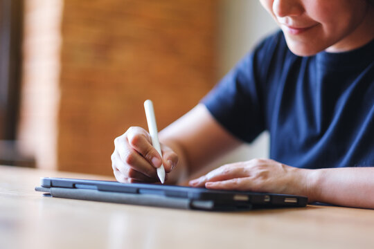 Closeup of a young woman using stylus pen technology for working and writing on digital tablet screen