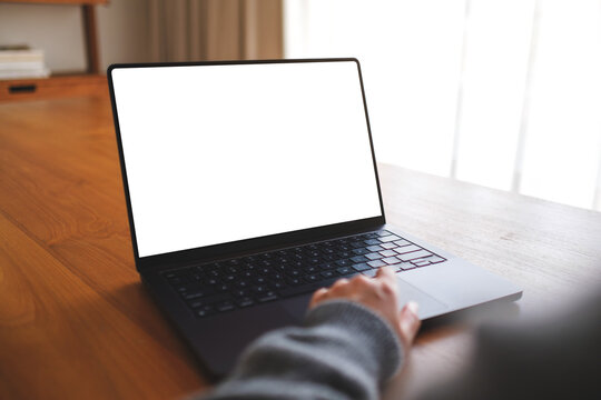 Mockup image of a woman working on laptop computer with blank white desktop screen at home