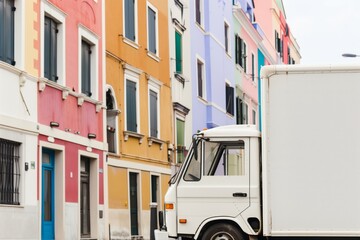 white food truck with its blank side facing a row of colorful buildings