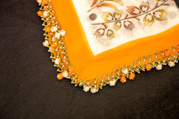 Hand-knitted scarf and headscarf samples, handmade embroidered and orange head scarf close-up.