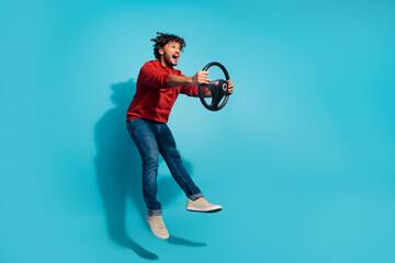 Full body length photo of overjoyed curly hair hispanic guy driving his sports car jumping danger speed isolated on blue color background