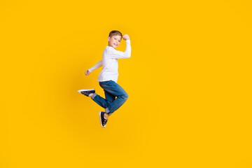 Fototapeta na wymiar Full length photo of cool lucky boy wear white shirt rising fists jumping high empty space isolated yellow color background