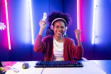African American girl gaming streamer team winner playing online fighting with Esport wearing...