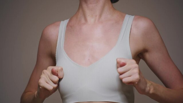 A young woman checks her breasts and shows a funny gesture.