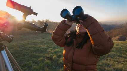 Amateur astronomer observing skies with binoculars and telescope