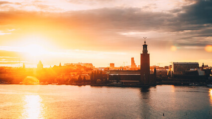 Stockholm, Sweden. Scenic Skyline View Of Famous Tower Of Stockholm City Hall. Building Of Municipal Council Stands On Kungsholmen Island. Sunshine Above Famous And Popular Place In Sunset Sunrise. - 764608275