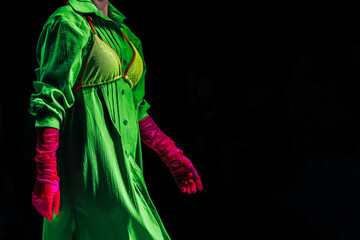 Interesting creative bright outfit green dress, pink gloves on black background
