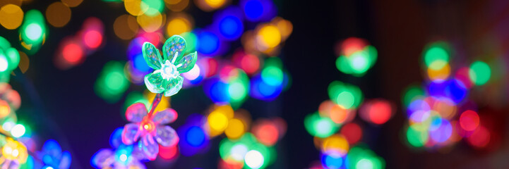 Multicolored garland flower against background of multicolored lights on Christmas night, beautiful...