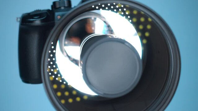 A professional camera on a tripod with an expensive lens with an aperture of 1.5 and a focal length of 85 mm, which reflects the ring LED light. Closeup. Macro. Shot in motion