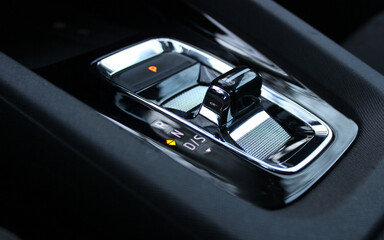 Illuminated symbols of the activated parking brake and neutral gear on the transmission selector in sports car closeup view
