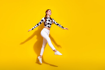 Full size profile photo of carefree lovely girl jumping empty space advert isolated on yellow color background