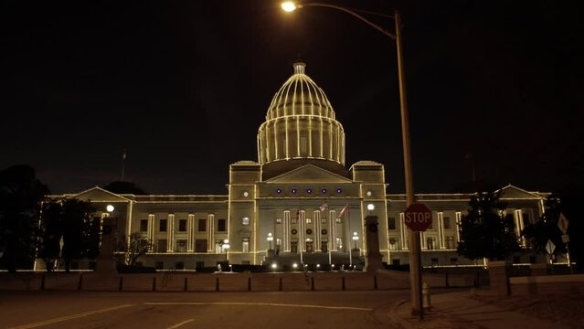 Arkansas state capitol in Little Rock Arkansas at night with holiday lights on the building with medium shot tilting down.