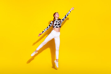 Full body photo of nice cheerful lady jump fly raise arm hold empty space isolated on yellow color...