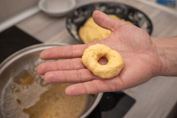 Hand holding a homemade doughnut before frying it