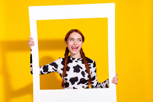 Photo of funky excited person hold album card tongue lick teeth look empty space isolated on yellow color background