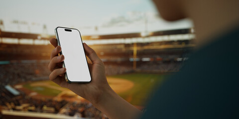 A hand holds a smartphone with a green screen at a baseball stadium - 764616297