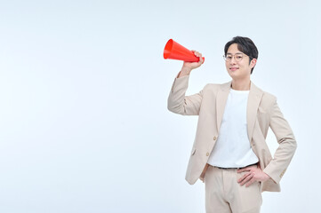 A young office worker in a suit and glasses poses with various facial expressions with a red loudspeaker.