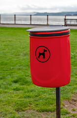 Dog poop bin. Red waste bin for dog poo disposal. Park bin with a dog picture to inform that poo bags should be placed inside. 