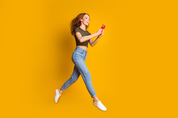 Fototapeta na wymiar Full length photo of cheerful girl blogger addicted user wear trendy clothes run read social media isolated on yellow color background