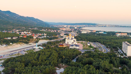 Fototapeta na wymiar Gelendzhik, Russia. Cathedral of St. Andrew the First-Called. The text at the entrance to the city is translated as Gelenzhik-City Resort. Sunset time, Aerial View