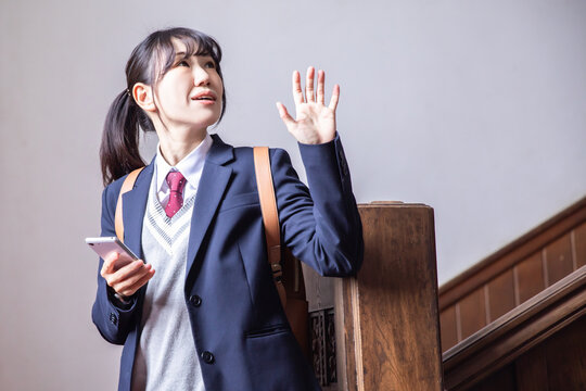 手を振る女子高生　登下校　携帯電話　high school girl going to school