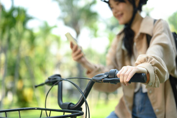 Cropped shot of smiling young woman using mobile phone while sitting on a bicycle