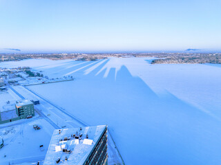 Aerial view over the frozen sea with the shadow of the tower of Helsinki