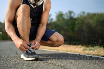 Sportsman tying shoelace getting ready for jogging or cardio workout. Healthy lifestyle concept - obrazy, fototapety, plakaty