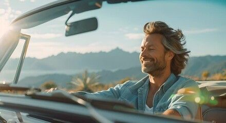 Man enjoying drive in convertible, mountainous backdrop, sunset light, happy, carefree.