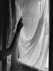Hand is reaching out to window, and curtains are drawn. Image has mood of curiosity and longing
