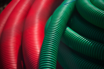 Red and green corrugated hoses are rolled into coils - 764649082