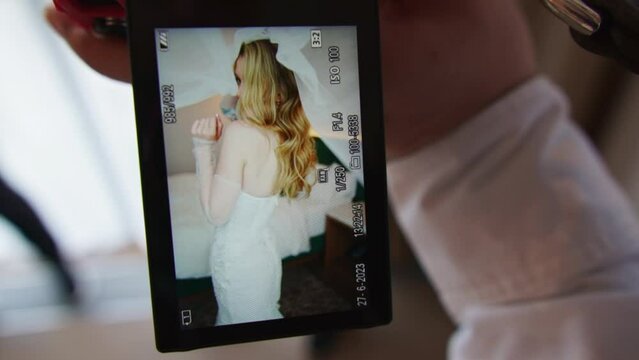 The photographer shows photos of the bride on the camera screen. 