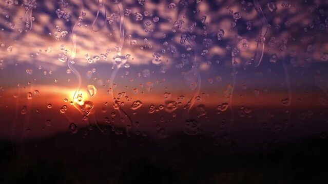 Animated rain drops flow down the glass in the evening sunset