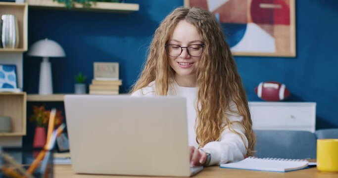 Business lady working remotely sitting at home using laptop. Student typing on computer sitting at wooden table indoors. People and technology, Distance education and e-learning concept.