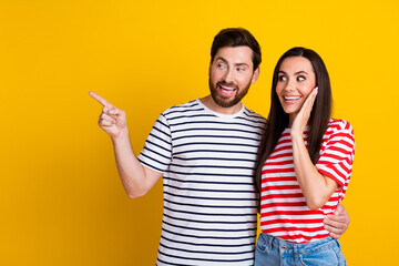 Photo portrait of nice young couple point look empty space amazed expression wear trendy striped outfit isolated on yellow color background