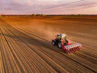 Aerial shot of a farmer seeding, sowing crops at field. Sowing is the process of planting seeds in...