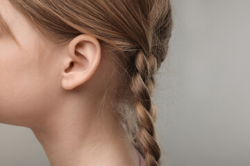 Hearing problem. Little girl on grey background, closeup of ear. Space for text