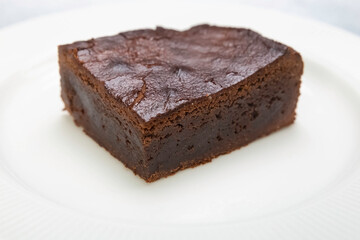 A piece of brown sponge cake on a white plate on table