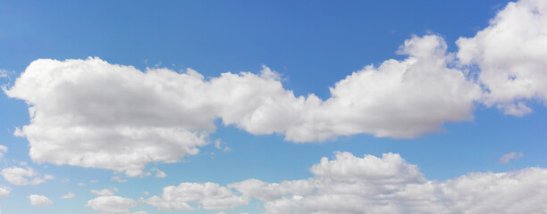 Expansive blue sky with white cumulus clouds, representing natural minimalism and serenity. Banner