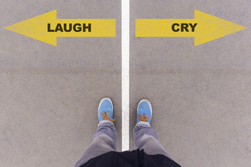 Laugh or Cry choice, text on asphalt ground, feet and shoes on floor