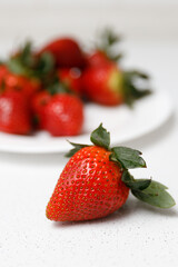 Juicy red strawberries lie on a white saucer