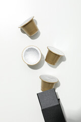Golden coffee capsules on black box on white background, top view