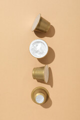 Golden coffee capsules on beige background, top view