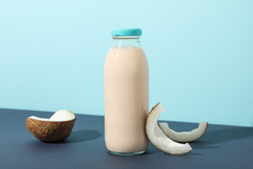 Bottle of alternative milk and coconut on blue background