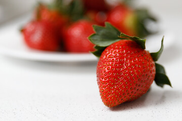 Juicy red strawberries lie on a white saucer