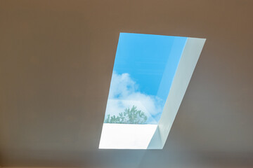 Open roof window in the apartment,Window in the ceiling,open window against blue sky and clouds,Minimal Modern architecture.