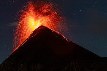 Volcano fuego erupting with a fire explosion of orange lava or magma at night with long exposure in guatemala seen from acatenango