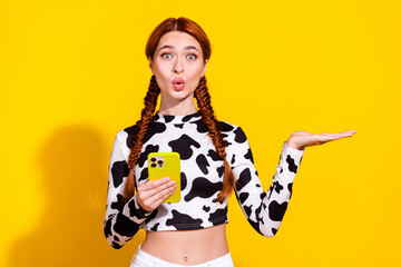 Photo of excited flirty lady dressed cowskin print top texting modern device showing arm empty space isolated yellow color background - obrazy, fototapety, plakaty